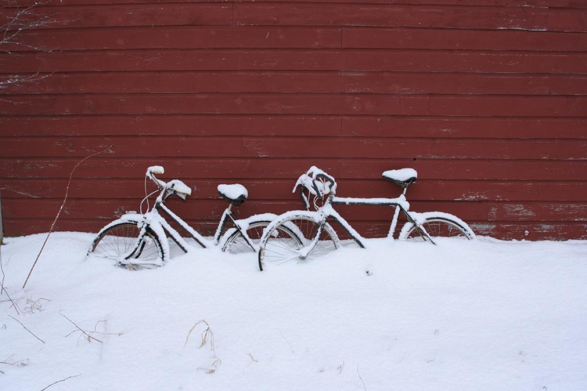 Winter scene with snow on bicycles against a red barn on West Street in Sandisfield