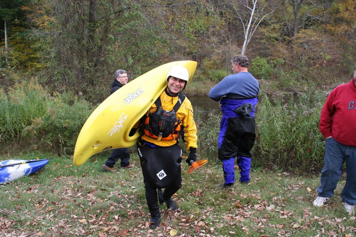 Man carrying a yellow Kayak near the Farmington River  in Sandisfield