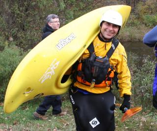 Man carrying a kayak walking away  from the Farmington River in Sandisfield